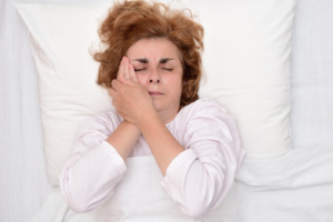 Woman lying awake in bed because of a toothache